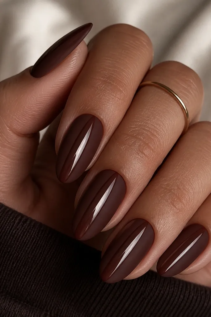 Medium almond nails painted oxblood brown with a centered cat-eye stripe. The nails are matte everywhere except the stripe area, which stays glossy and mirror-like.