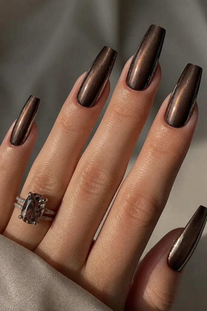 Long coffin nails in smoky dark brown with a centered cat-eye stripe. A thin strip of silver foil sits along one side edge from mid-nail to tip, like a metallic border.