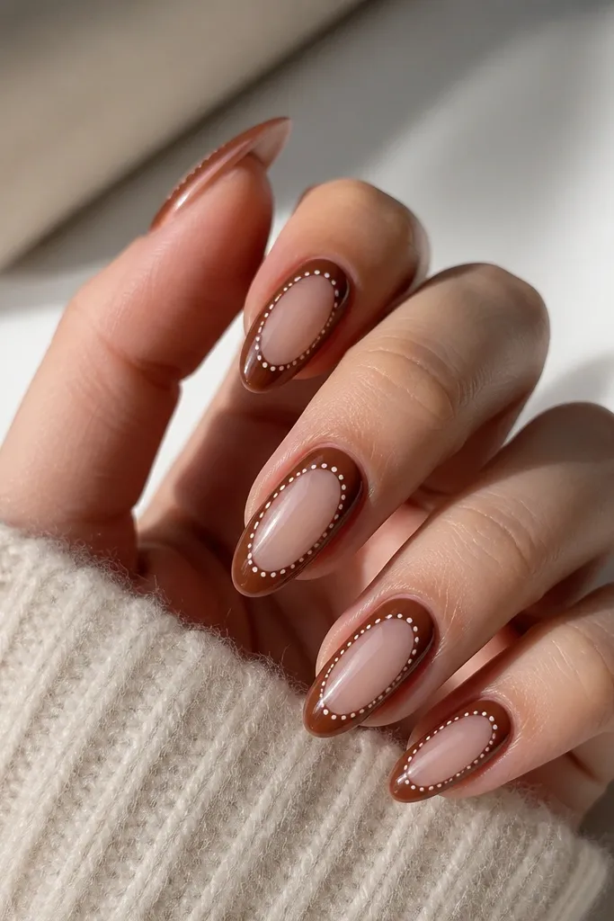 Mocha brown nails with a clear cutout section at the center. Around the clear cutout, there are white polka dots forming a neat outline, glossy finish.