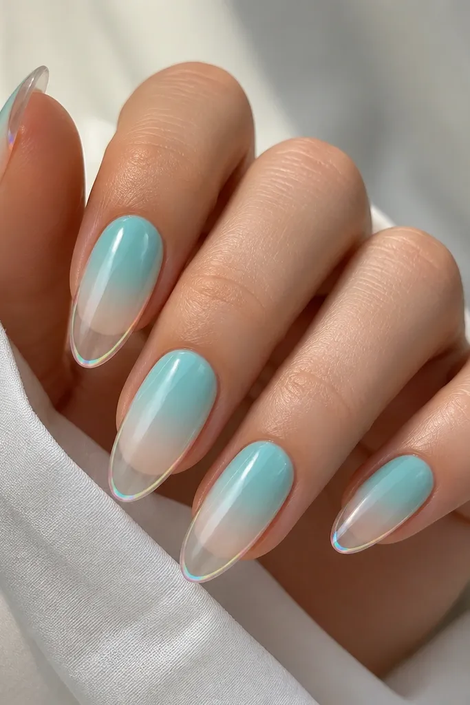 Long oval nails with aqua fading into clear; a thin iridescent chrome outline traces the nail's perimeter and tip edge.
