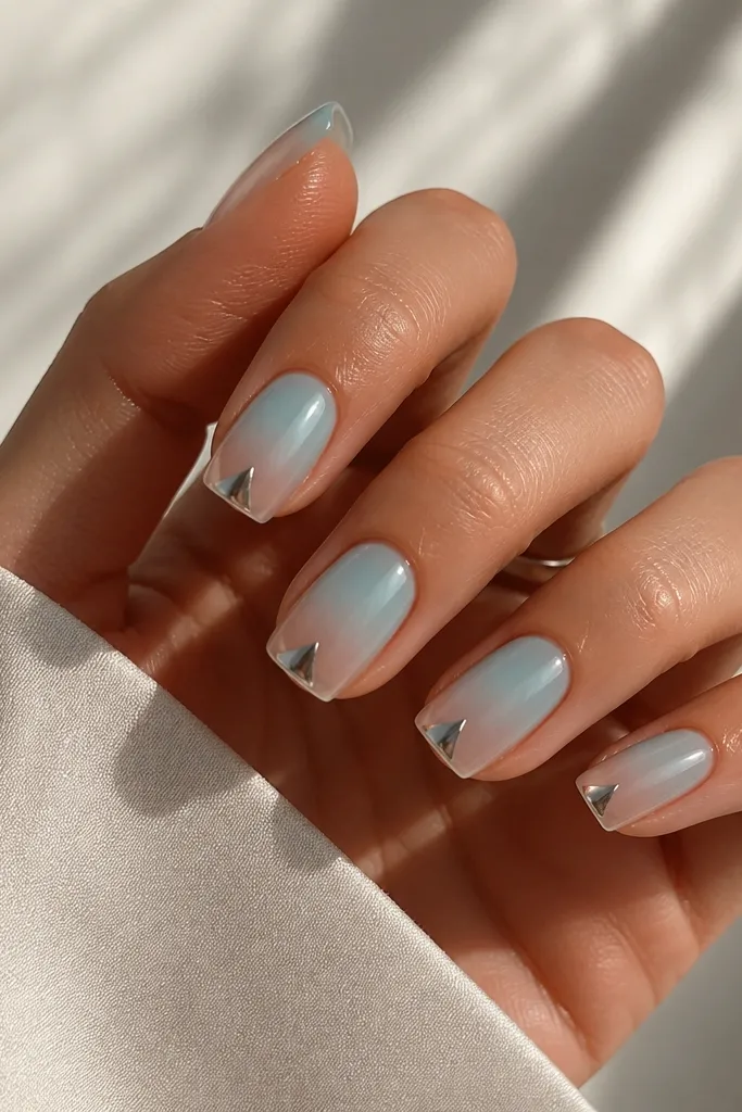 Medium squoval nails with aqua ombre fading to clear; a small chrome triangle sits centered at the tip, with mirror shine.