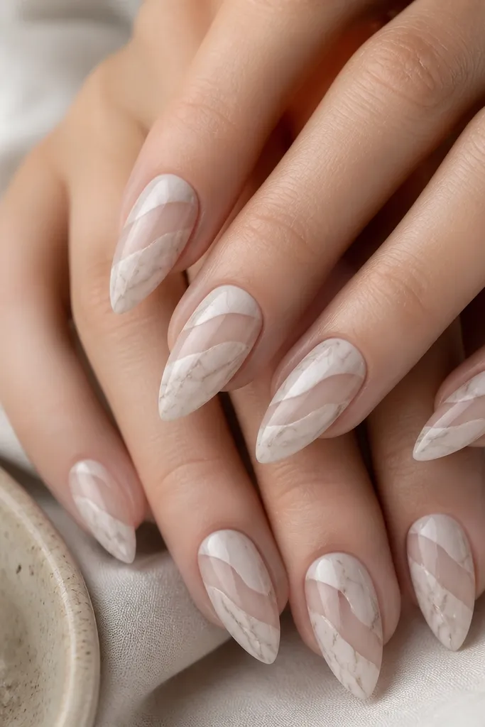 Short stiletto nails with taupe marble on a milky base; two diagonal clear cutout sections appear on each nail near the center; marble lines are thin and light; glossy finish.