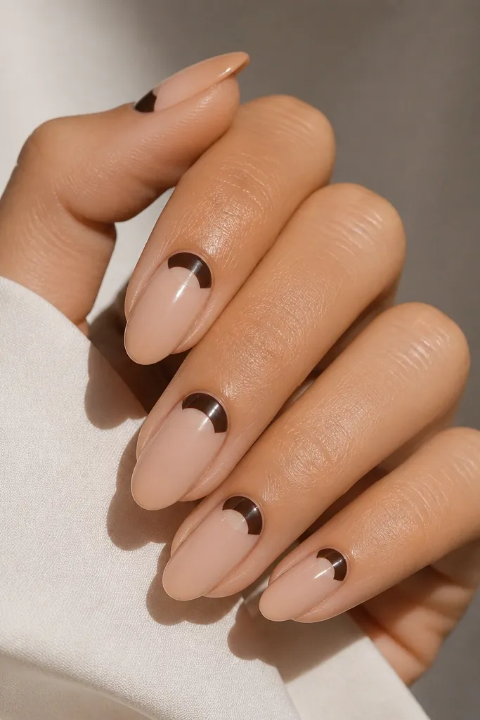 Medium almond nails with a nude base. At the cuticle, there are clean espresso half-moon shapes that stop short of the skin, leaving a clear crescent. The rest is glossy.