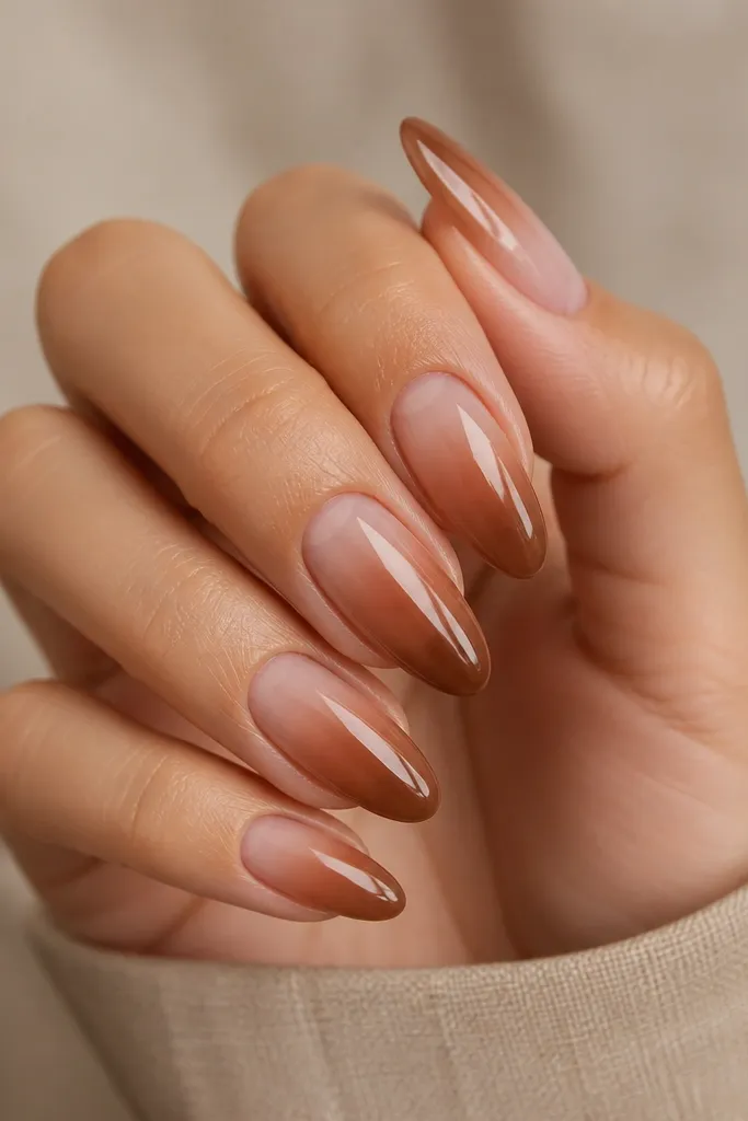 Long almond nails with a smooth caramel-to-nude ombré. The caramel is strongest at the tip and fades into a milky nude near the cuticle. Finish is glossy and the gradient is soft.