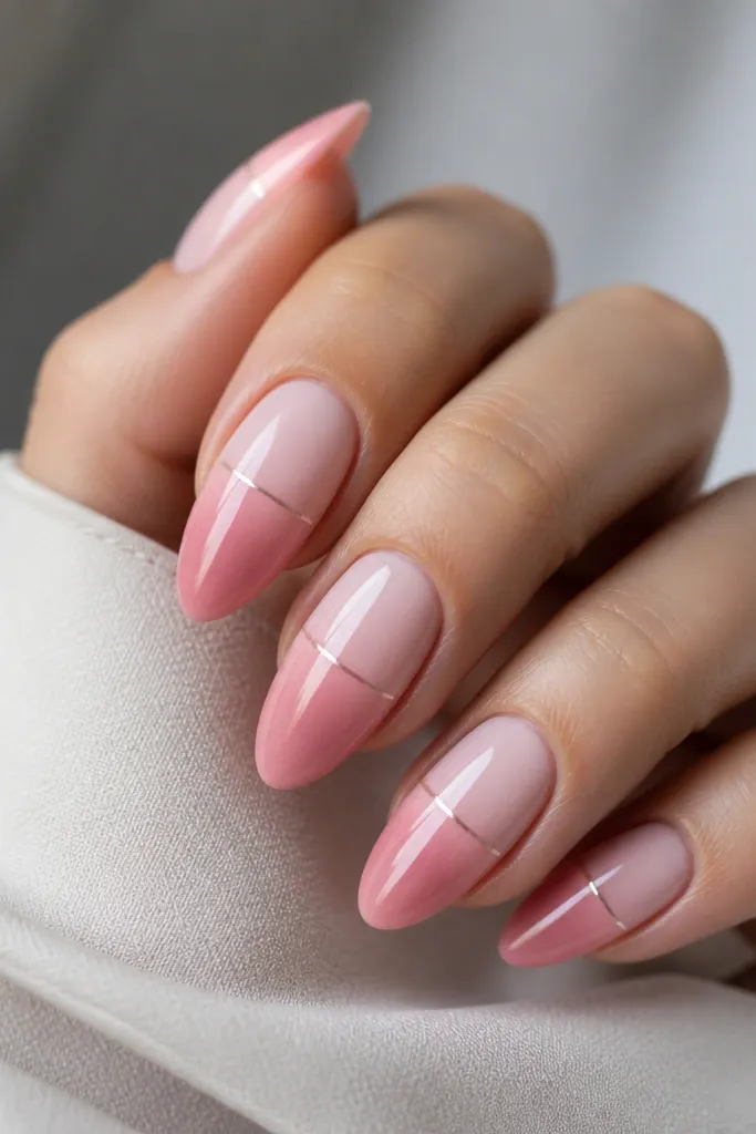 Almond nails with a pale pink to medium rose ombre. A thin pink chrome line runs horizontally like a waterline across the middle of each nail, with soft reflections above it.