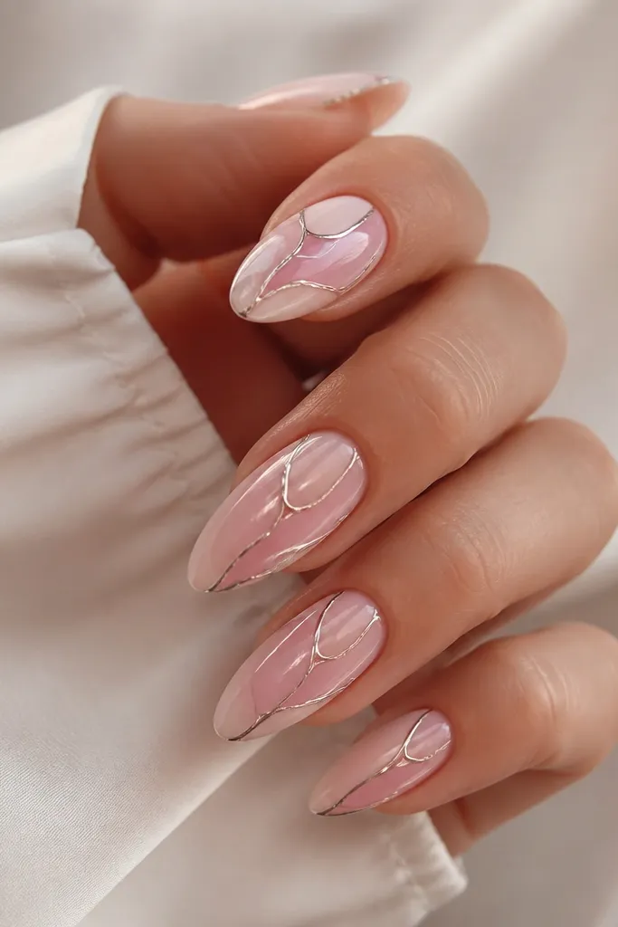 Almond nails with a pale pink ombre. Chrome is applied along irregular edge lines like stained glass panels, leaving small clear gaps. The reflections follow the edge pattern instead of covering everything uniformly.