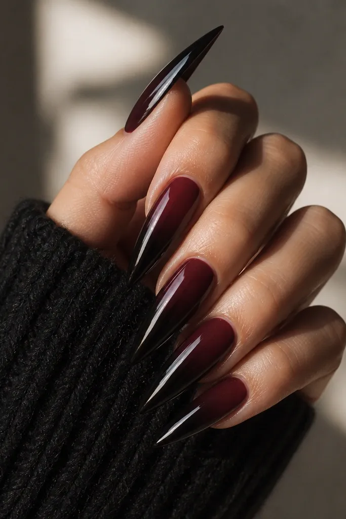 Long stiletto nails with a black cherry fade into near-black at the tips, finished with black mirror chrome that reflects dark highlights.