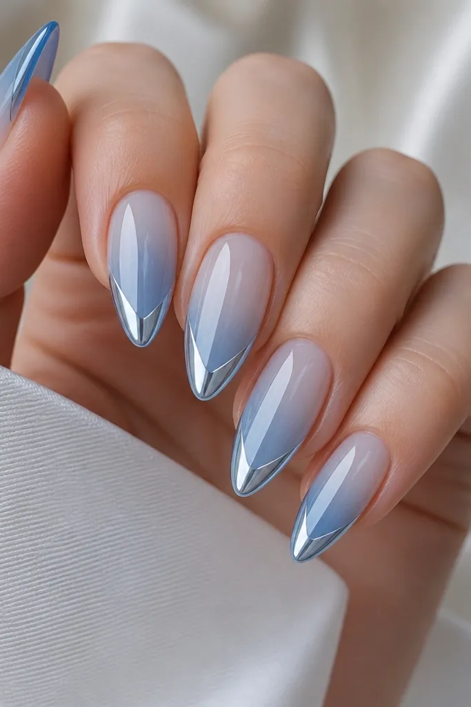 Almond nails fading from translucent ice blue at the cuticle to deeper icy blue at the tips, with a V-shaped mirror chrome in the center of the tip.
