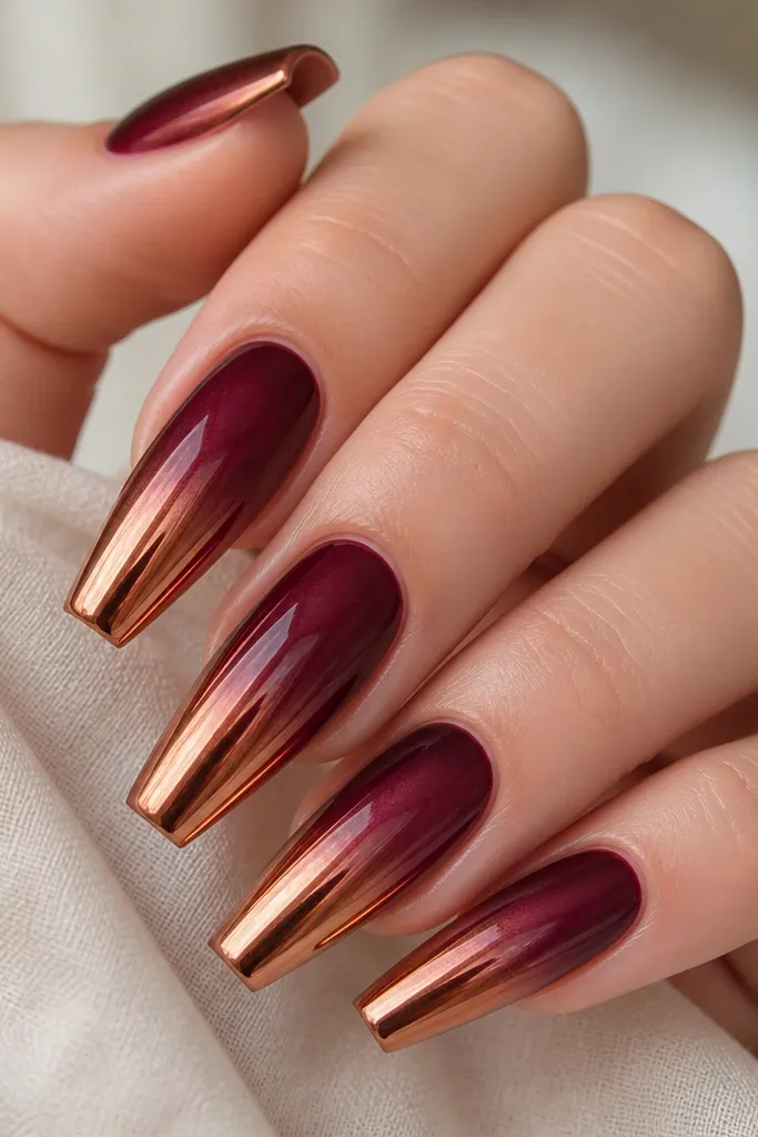 Coffin nails with a burgundy-to-wine ombre fading into copper chrome at the tips, reflecting warm copper highlights.