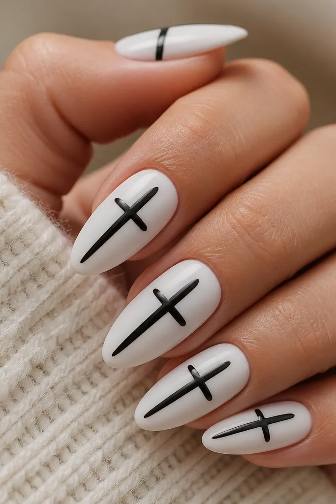 Short nails are matte white. Each nail has a glossy black cross made of two thin lines that intersect at the center, with a little shine compared to the matte base.