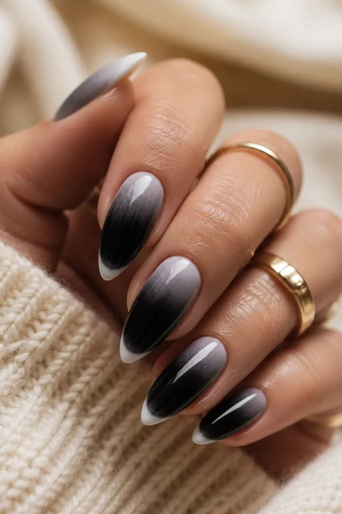 Short nails with a smooth black ombre that fades upward into clear/nude near the cuticle. At the very tip, there's a white thin border line across the edge like a micro french.