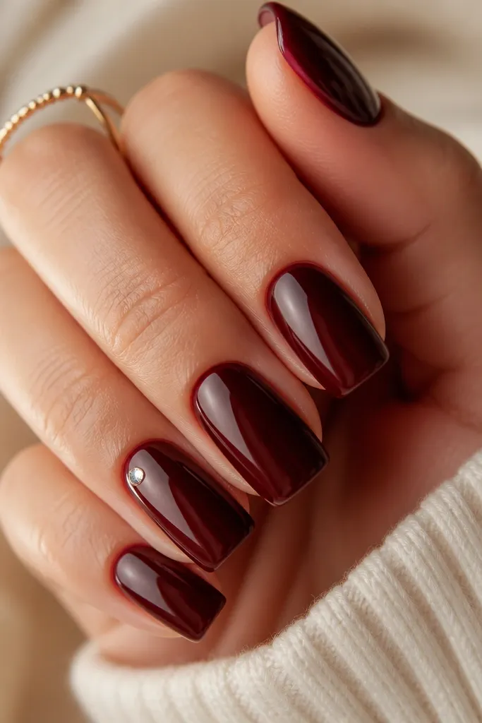 Deep mahogany brown nails, high-gloss, each nail has a single tiny rhinestone placed near the sidewall close to the cuticle.