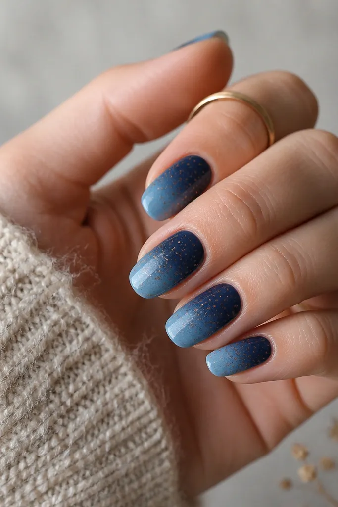 A blue ombre from deep navy at the cuticle to lighter denim at the tip. Brown dots fade as they get toward the tip: more dots near the cuticle, fewer near the end.