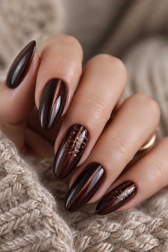 Almond nails. Very dark brown cat eye stripe centered. On two nails, tiny copper foil specks are scattered around the stripe, mostly in the upper half, with some irregular torn edges visible.