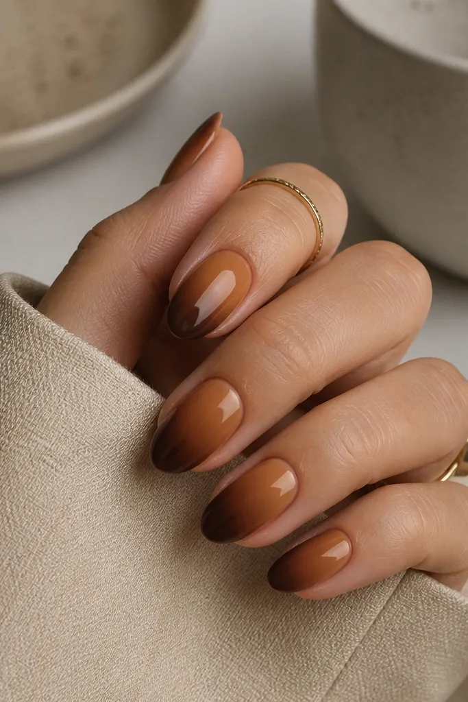 Short almond nails with a smooth caramel-to-brown ombre: lighter caramel at the cuticle fading into a deeper chocolate at the tip, with no harsh line.