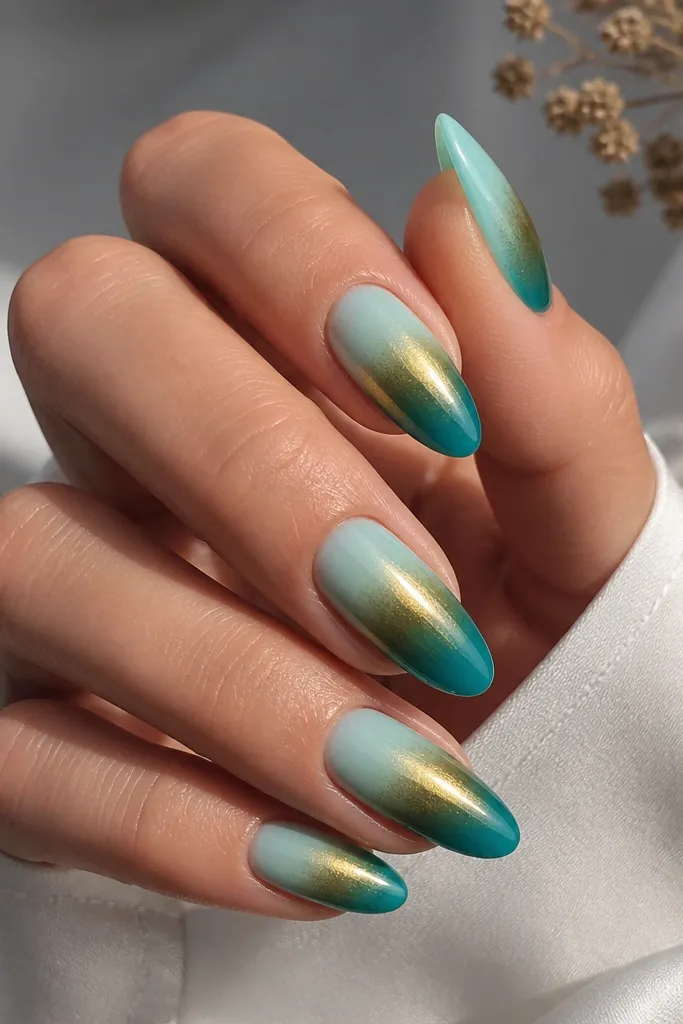 Long almond nails with turquoise fading from pale aqua near the cuticle to deep teal at the tip; gold chrome is applied as a thin glossy layer over the middle, not the whole nail.