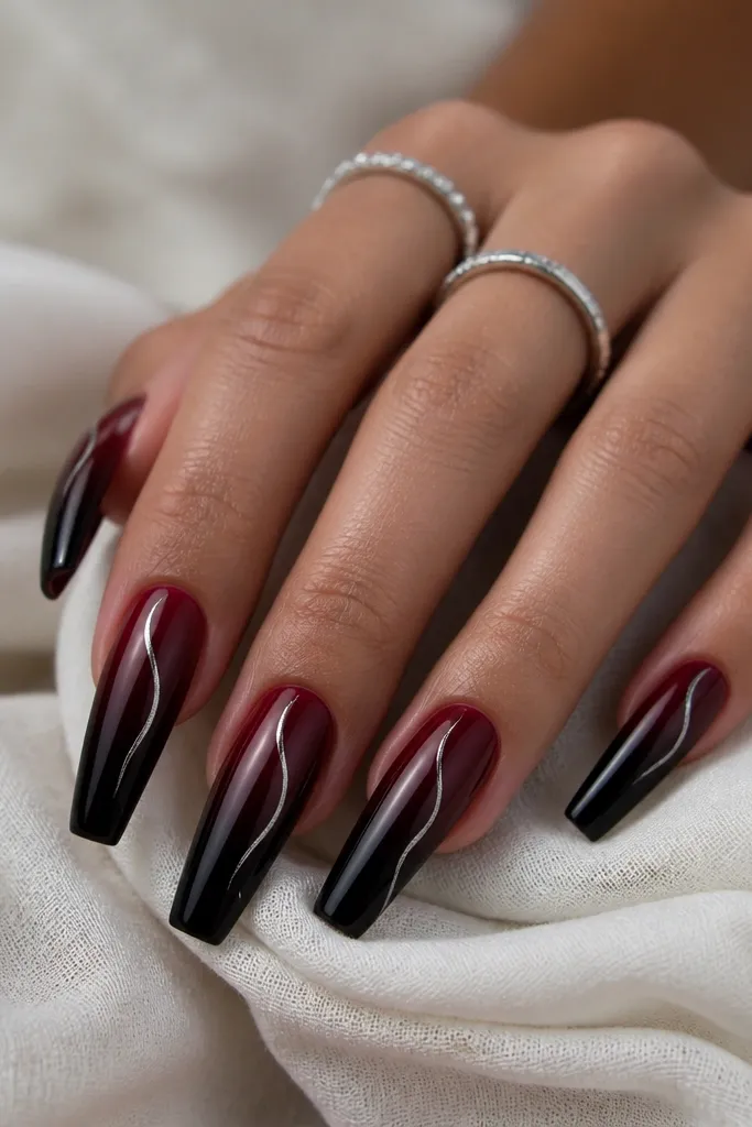 Long coffin nails with a black cherry ombre from deep berry near cuticle fading into near-black at tips; silver chrome is drawn as a thin curved vein starting near the cuticle.