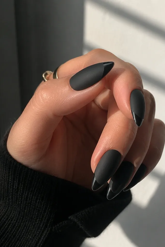 Short stiletto nails are matte black everywhere except the last 2-3 mm of the tip, which is glossy and reflective.