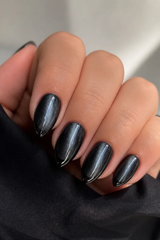 Short stiletto nails in black cat-eye gel; a bright silver streak runs down the center of each nail, with the tip edge slightly defined.