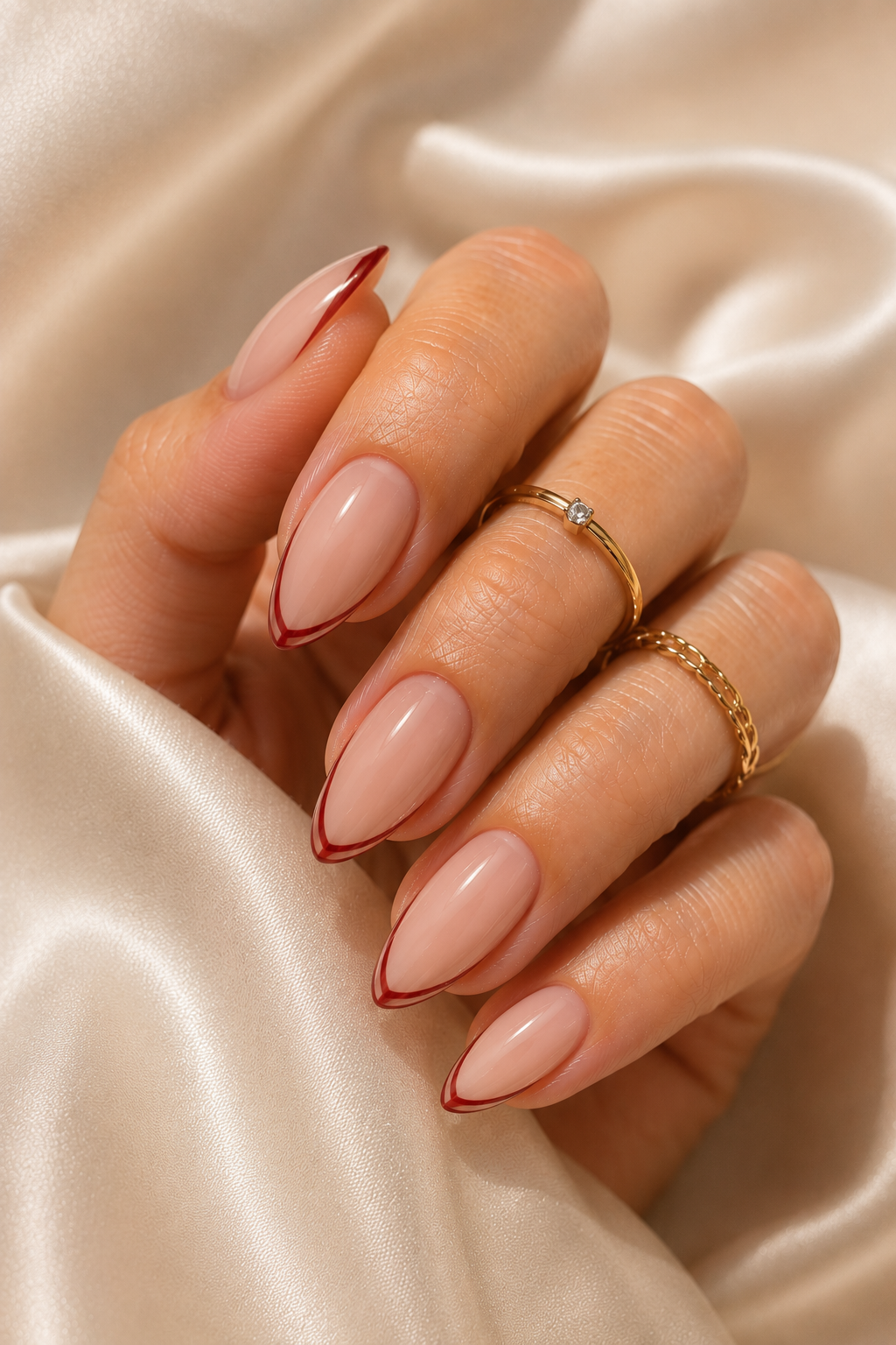Short stiletto nails with sheer nude base and glossy. The tips are painted classic red, but the red is outlined with a thin nude border to create a double-layer effect.