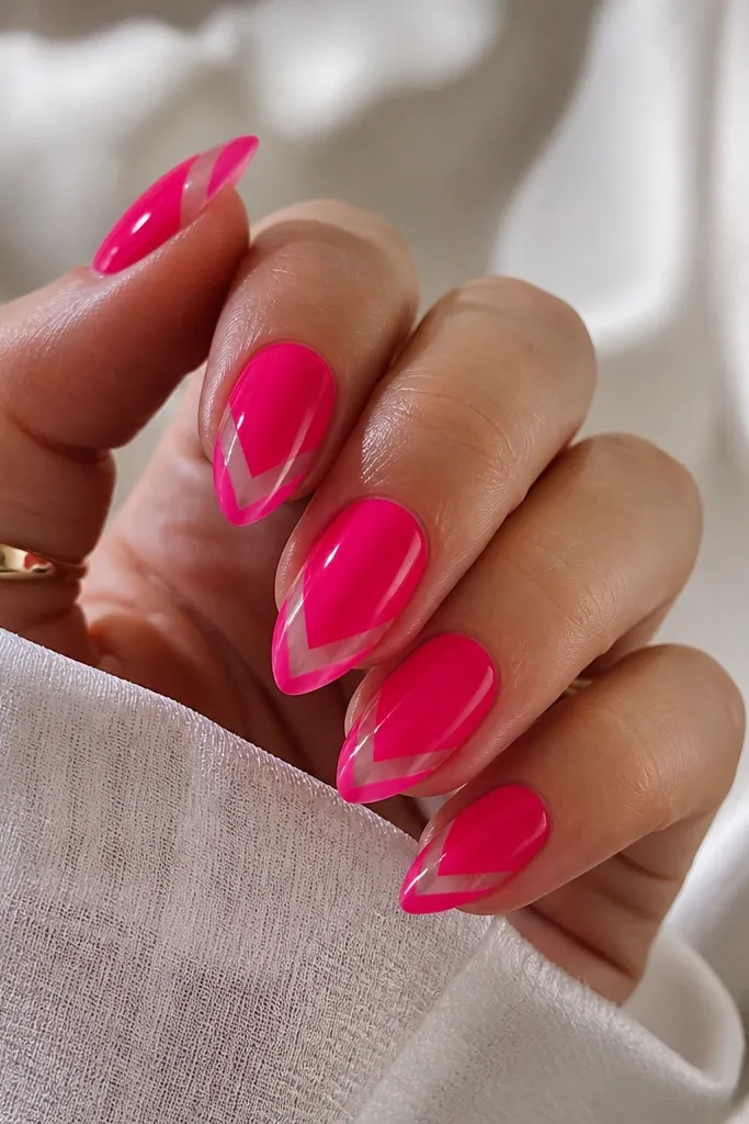 Short stiletto nails in glossy hot pink jelly. A clear V-shaped negative space runs from the tip toward the center, leaving the V unpainted and glassy.