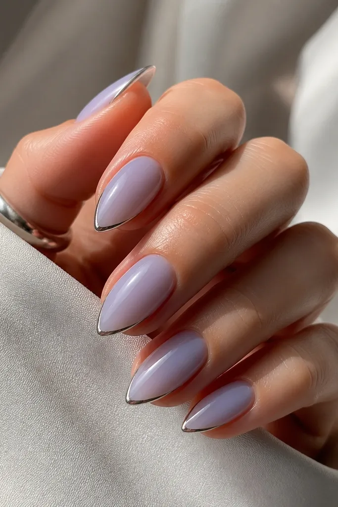 Compact short stiletto nails with sheer lavender base. Tips have a thin silver metallic line instead of white, following the micro French curve.