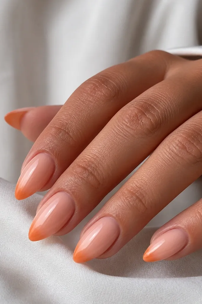 Short stiletto nails in glossy peach nude. The last 2-3 mm fades from peach into a stronger orange at the tip point.