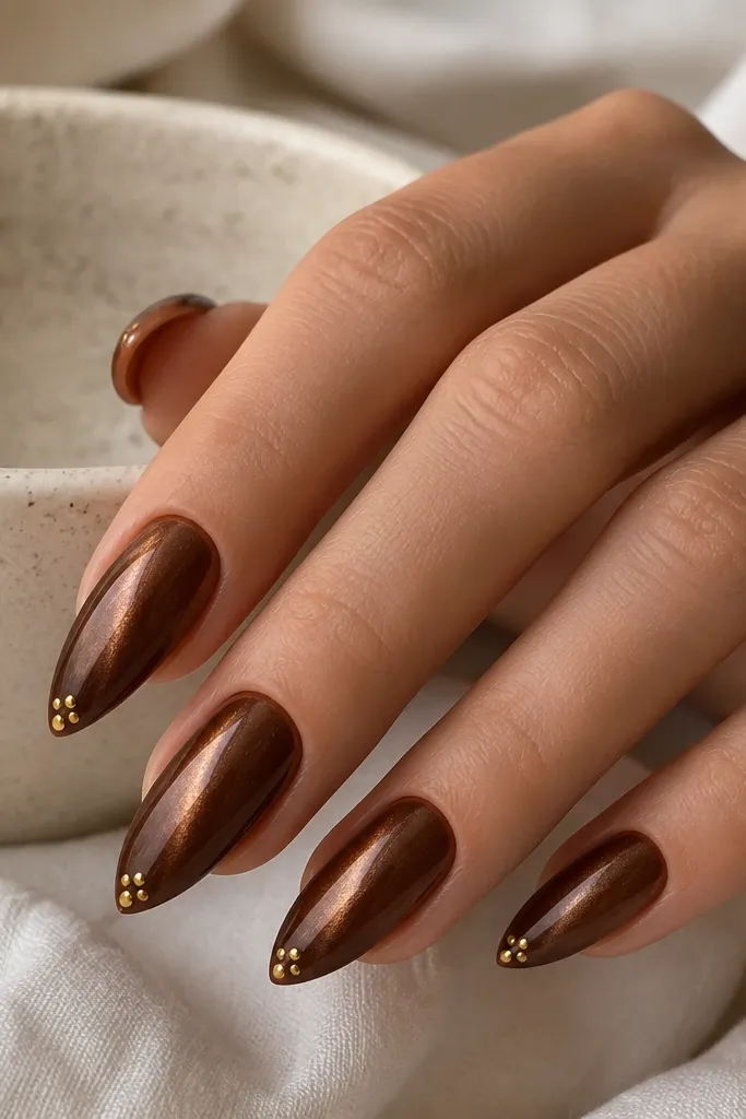 Warm brown cat-eye nails; shimmer line is straight; at the tip there are 3-5 tiny gold dots clustered in a small triangle, glossy finish.