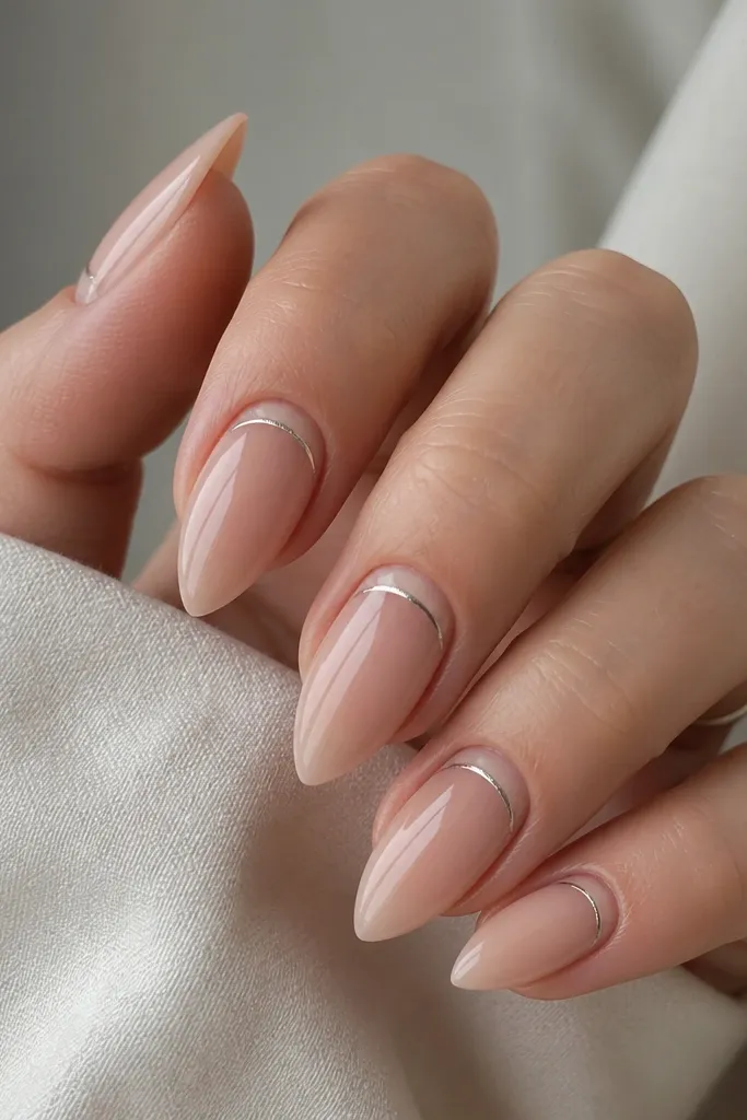 Short stiletto nails with a sheer clear nude base. A thin half-moon cutout sits at the cuticle edge in natural color, outlined with a silver line. The rest of the nail is glossy and bare-looking.