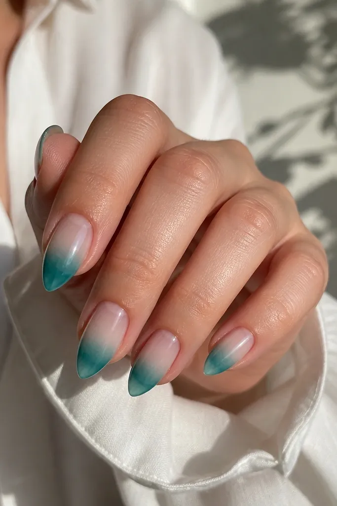 Short stiletto nails with a teal jelly gradient. The color starts semi-transparent at mid-nail and becomes deeper teal near the tip. The very tip has a clear edge so the point looks glassy.