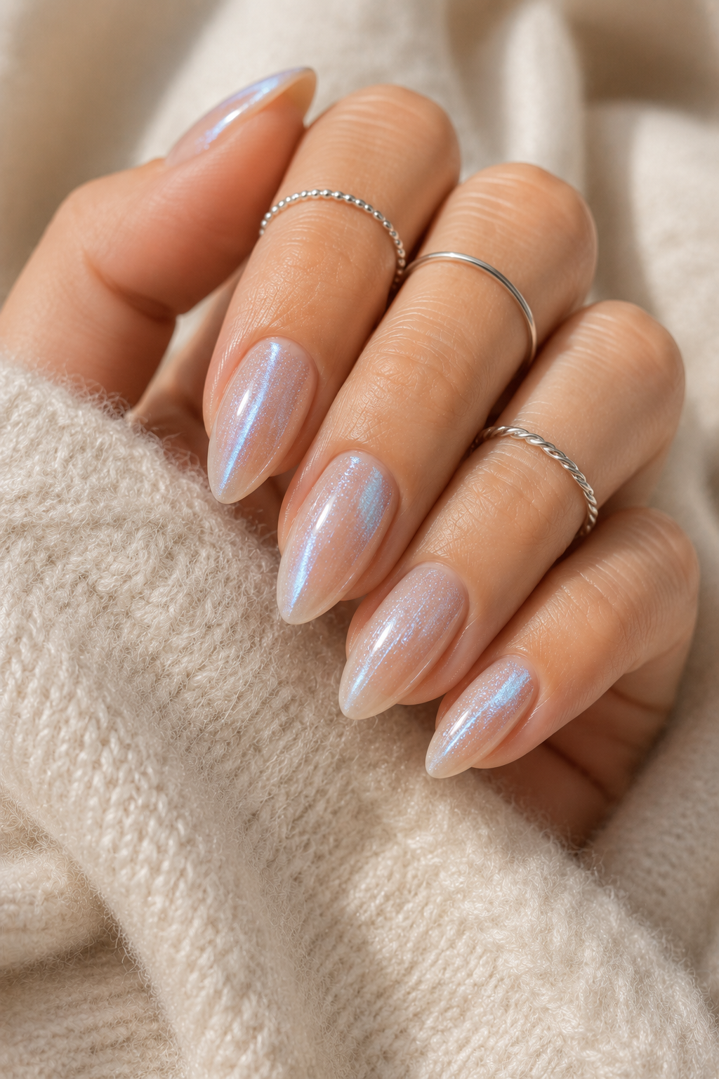 Short stiletto nails with a sheer nude base. Over it sits an icy blue frost topcoat layer that looks like powdered shimmer, darkest at the tip and lighter toward the center. The finish is frosty, not glittery.