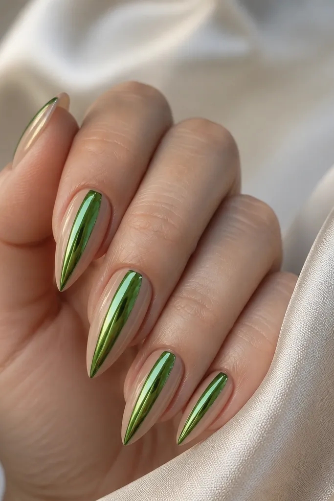 Short stiletto nails with two nude side panels on each nail. The center is covered in metallic green chrome that looks mirror-bright. The nude panels are clean and symmetrical.