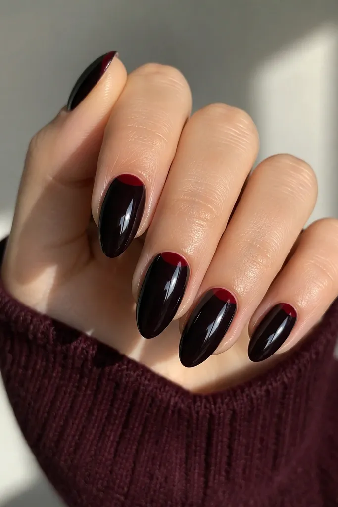 Short stiletto nails with a deep black cherry glossy base. At the cuticle area, there's a thin wine-red line shaped like a shallow curve. The line is crisp and reflective.