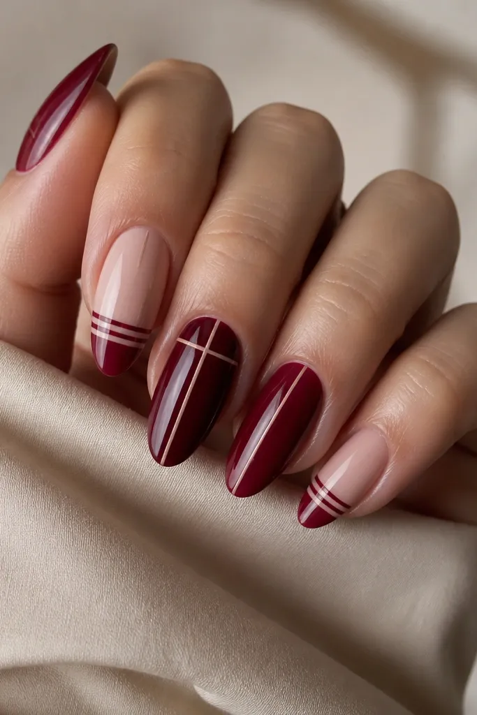 Square-short nails in deep cherry red with two thin diagonal silver lines on two accent nails, clean tape edges, glossy finish.