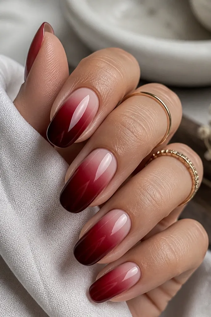 Deep cherry red nails with a soft blush-pink fade near the cuticle blending into solid red toward the tips, glossy finish.