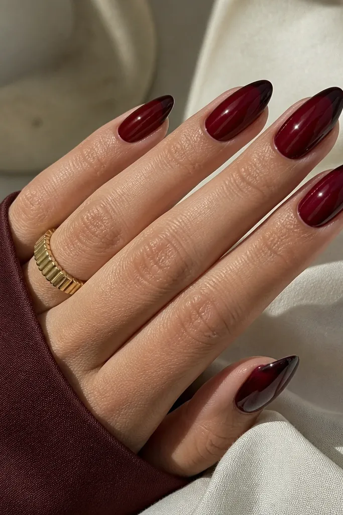 Almond nails with a deep red base and a French tip in a darker blackened burgundy. The tip line is crisp and narrow.