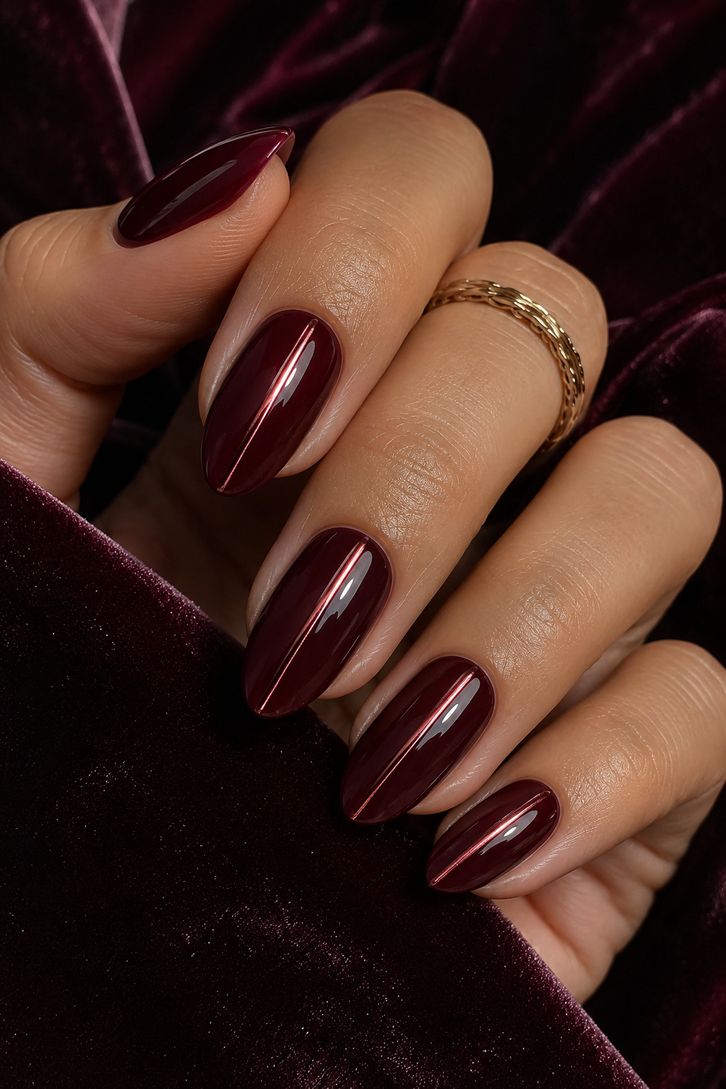 Five short squoval nails with a deep oxblood base; chrome is concentrated in a vertical mirror stripe in the exact center of each nail, leaving the sides fully red and matte-looking.