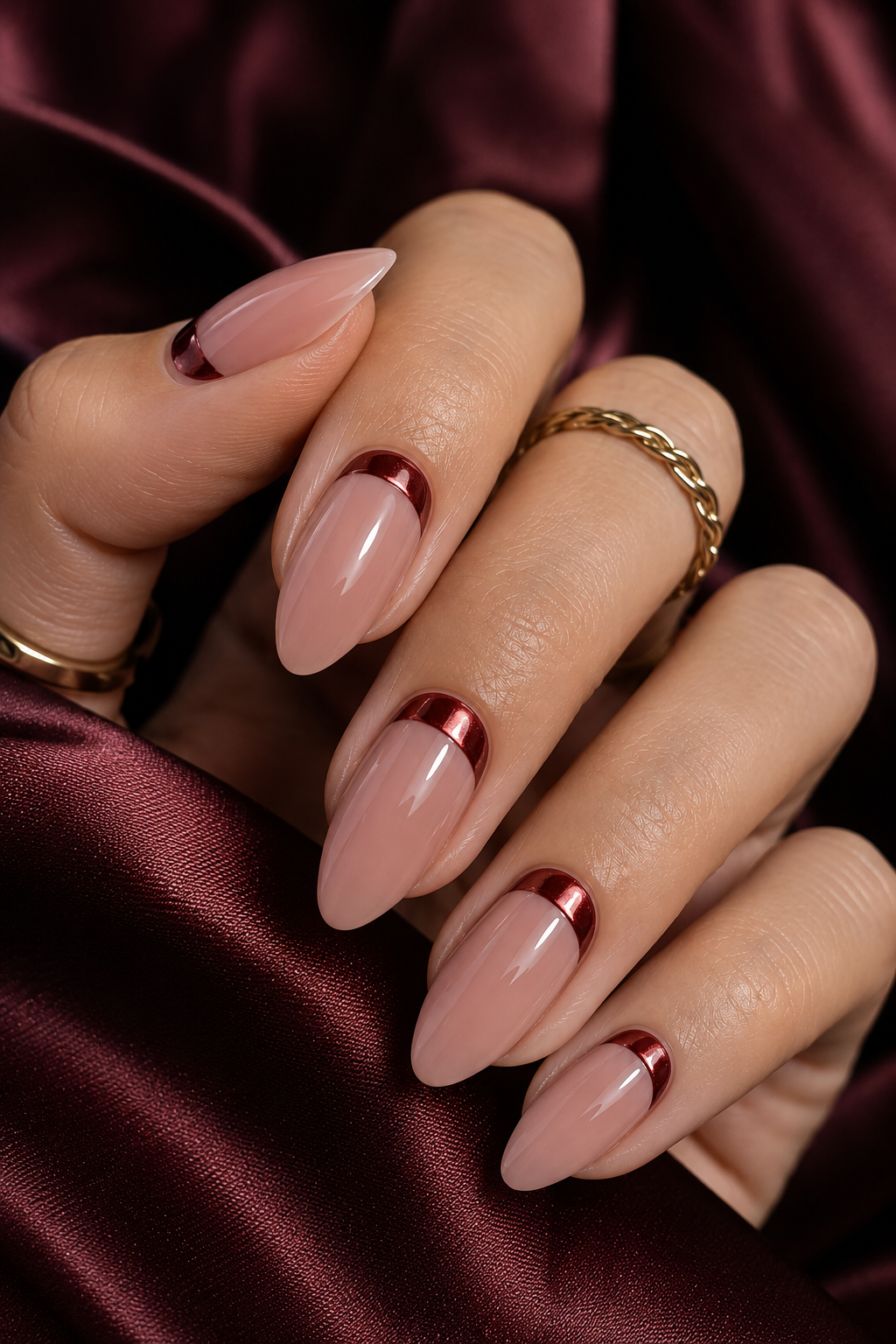 Five short almond nails with deep wine red bases; a chrome half-moon sits at the cuticle edge, forming a curved crescent that stops before the sides.