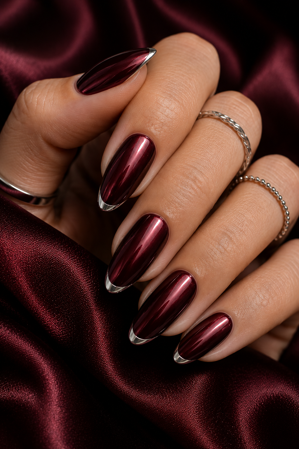 Short round nails with deep oxblood chrome; each tip has a tiny silver crescent at the center, like a small moon at the very edge.