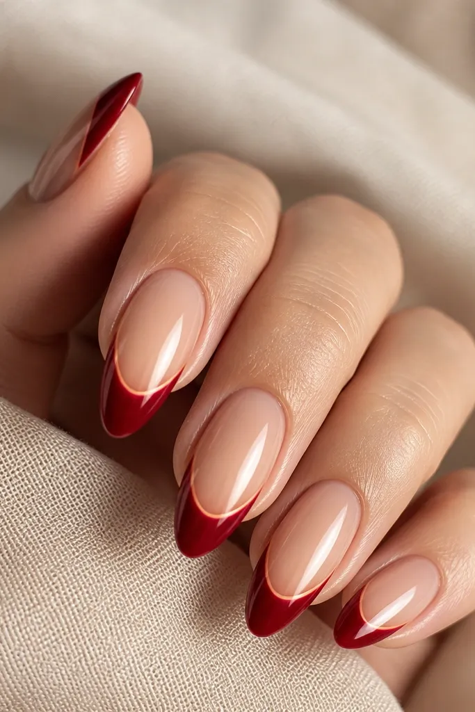 Squoval nails with a nude-beige glossy base; the french tips are a brighter cherry red and the line is crisp and centered.