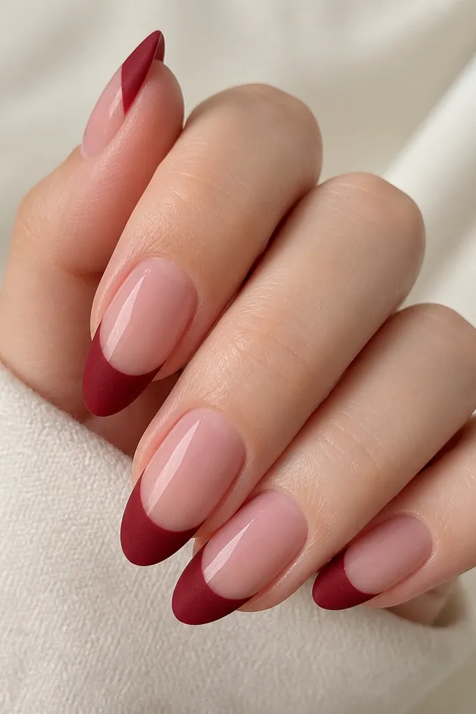 Almond nails with a sheer glossy-pink base; the french tips are deep red with a soft matte velvet finish and no glitter.