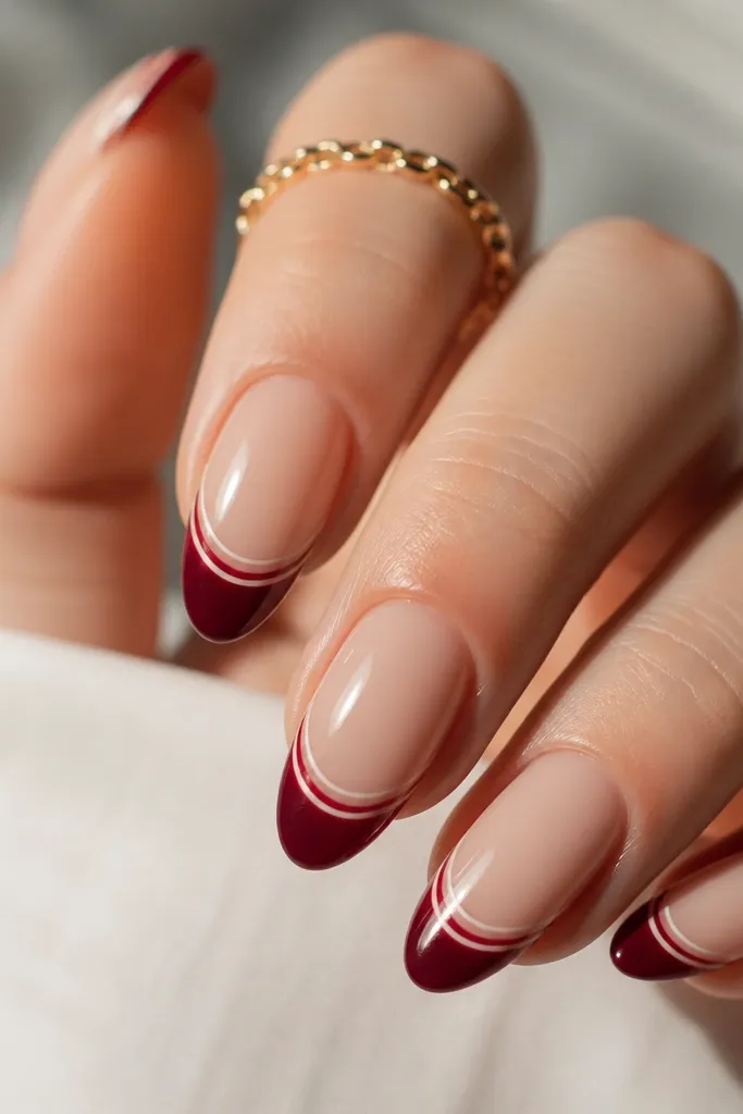 Almond nails with a milky pink base; deep wine red french tips have a razor-thin white line on both the inner and outer edges of the tip.
