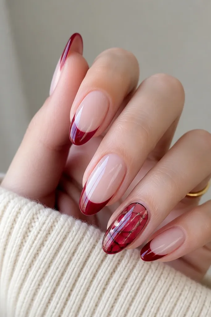 Almond nails with milky pink base; deep red french tips, and one accent nail has a stained-glass panel where the red outlines form a geometric window.