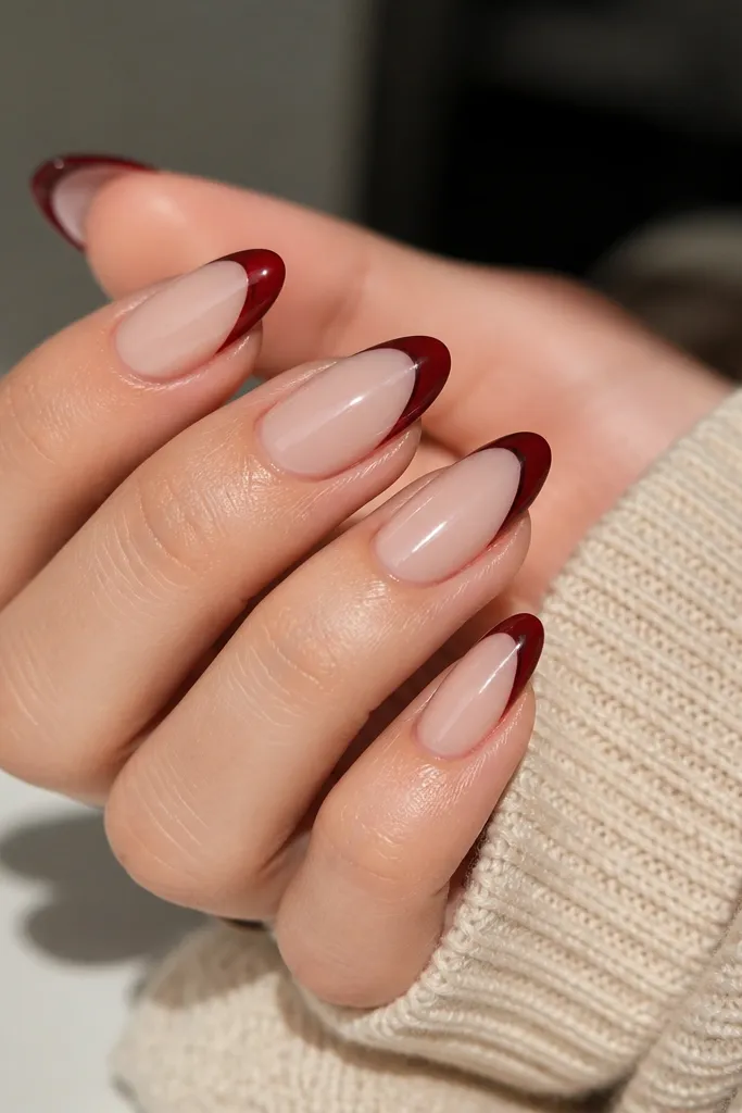 Almond nails with milky nude base; deep red french tips with a barely-there chocolate brown shadow just under the red line.