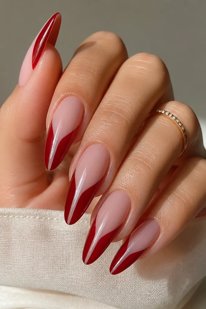 Long almond nails with nude base; deep red covers most of the french tip, but a thin clear negative stripe runs vertically through the center of the red.