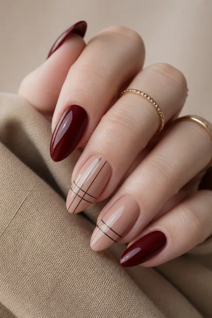 Deep red nails with thin black line segments forming a tiny grid on the accent nail; lines are short and spaced, not full squares.