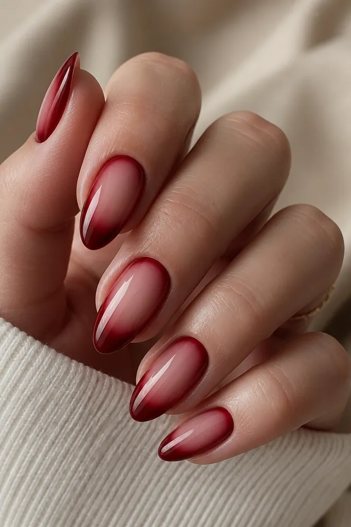 Nails with deep red fading into a nude center band that glows, then fading back to deep red toward the sides; glossy finish.