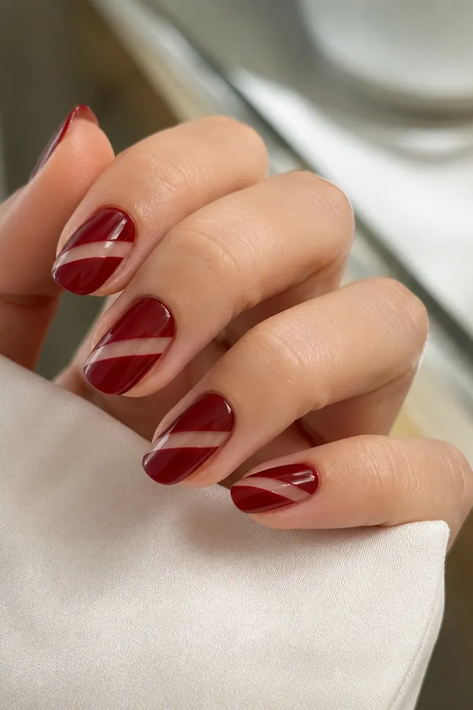 Medium nails with deep red polish covering most of the nail; a diagonal clear negative space panel cuts across from side to side; glossy finish.