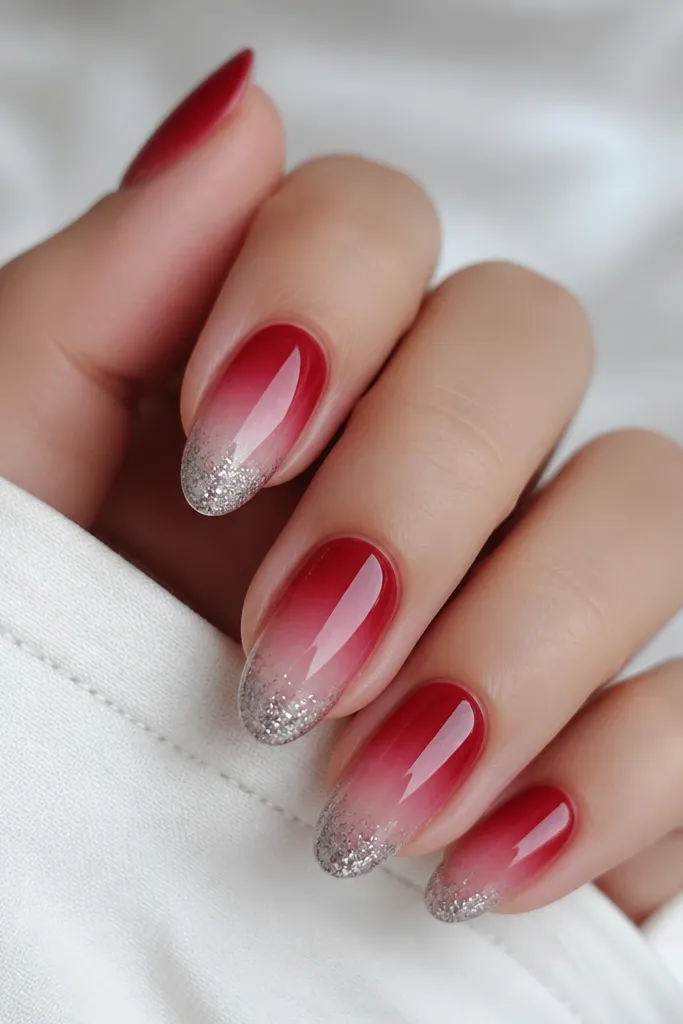 Medium oval nails with cherry red ombre fading to sheer pink; silver chrome is applied at the tip with a fine glittery sparkle texture.