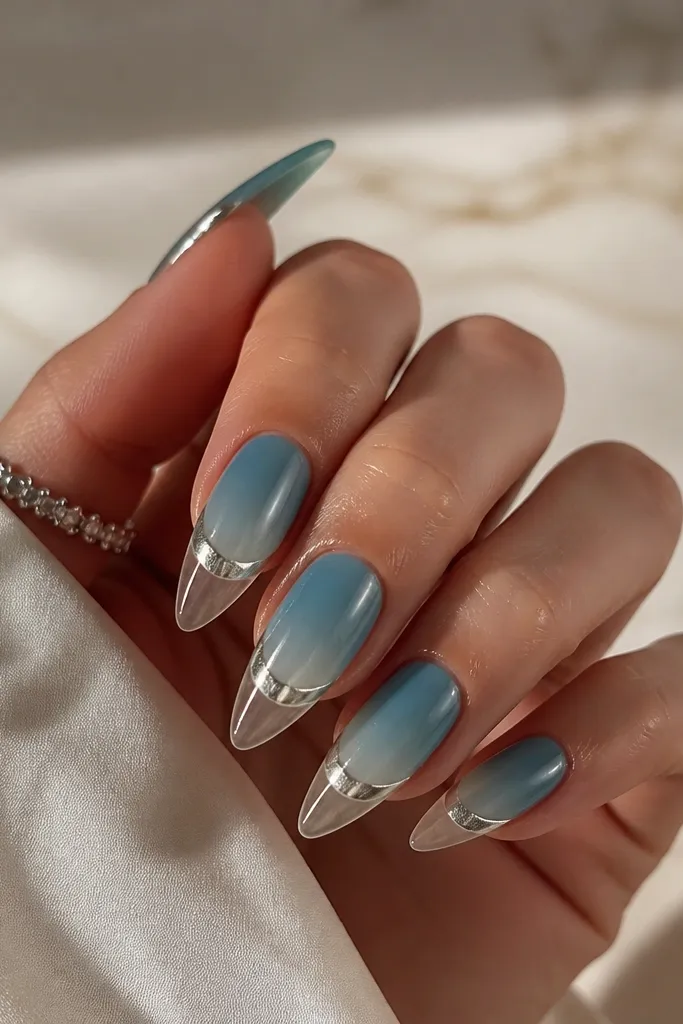 Long almond nails with teal ombre fading into clear; silver chrome forms a curved waterline band just above the tip.